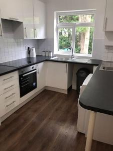 a kitchen with white cabinets and a sink and a window at Spacious Kosher Flat in Golders Green in London
