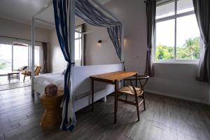 a bedroom with a bed and a table and windows at Baan Jai Dee Beach Front Hotel in Wok Tum