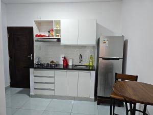 cocina con armarios blancos y nevera de acero inoxidable en Monoambiente en Condominio Boulevard en Trinidad