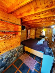 1 dormitorio en una cabaña de madera con 1 cama. en Cabañas Casa de Piedra en Trevelín