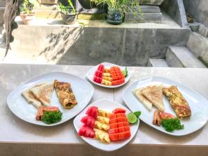 three plates of food with fruit and vegetables on a table at Heri house ubud in Ubud