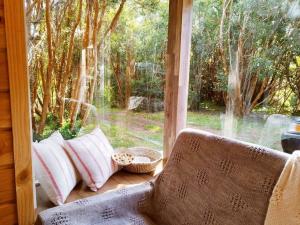 a window with pillows on a couch in front of a window at Arriendo Cabaña Entre Arrayanes. in Las Quemas del Salto