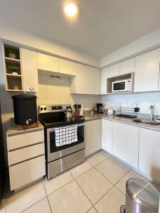 a kitchen with white cabinets and a stove top oven at Exclusive Apartment, Calzada Roosevelt in Guatemala