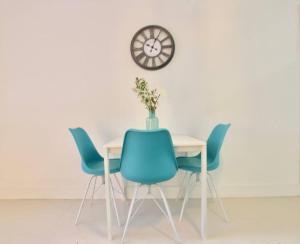 a dining room table with blue chairs and a clock at Modern 1/1, Half a Block from The Ocean in Miami Beach