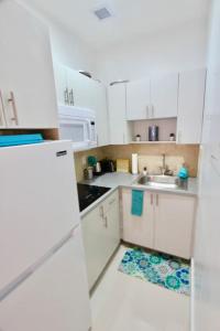 a white kitchen with a sink and a refrigerator at Modern 1/1, Half a Block from The Ocean in Miami Beach