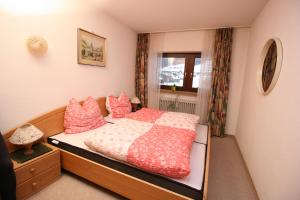 a bedroom with a bed with pink pillows and a window at Alpendohle in Reit im Winkl