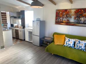 a living room with a green couch and a kitchen at ALOJAMIENTO AVENIDA DEL MAR CABAÑA LA SERENA in La Serena