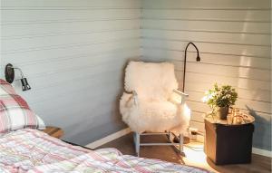 una silla blanca sentada en una esquina junto a una cama en Awesome Home In Laukvik With Kitchen, en Laukvik