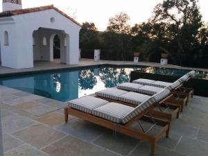 a group of lounge chairs next to a swimming pool at Exquisite Estately Villa in Woodside