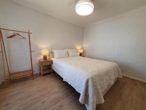 a white bedroom with a bed and a night stand at The African Reef in Geraldton