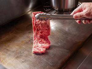 um pedaço de carne a ser cortado numa tábua de corte em KAMENOI HOTEL Atami em Atami