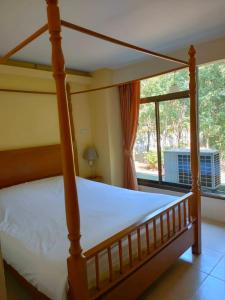 ein Schlafzimmer mit einem Himmelbett und einem Fenster in der Unterkunft โรงแรมมูนแอนด์ซัน Moon and Sun Hotel in Chiang Rai