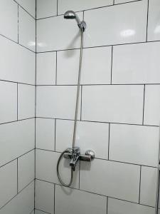 y baño de azulejos blancos con ducha y manguera. en Departamento duplex 4, en Puerto Natales