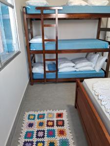 une chambre avec deux lits superposés et un tapis dans l'établissement 03 Dormitorios de Frente a Praia do Itararé / SV, à São Vicente