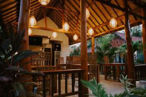 珀尼达岛Sawit Garden Cottages的有木桌椅和灯光的餐厅