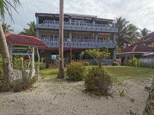 un gran edificio en la playa con palmeras en Tropicasa Siquijor Seafront Guest House en Solangon