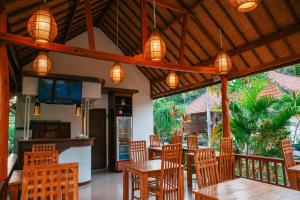 a restaurant with wooden tables and chairs and lights at Sawit Garden Cottages in Nusa Penida