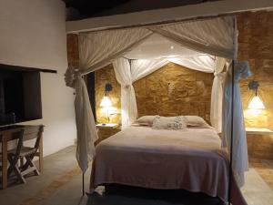 1 dormitorio con cama con dosel y escritorio en Mirador Escondido del Chicamocha a 22km de Barichara, en Villanueva