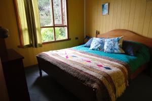 1 dormitorio con 1 cama con sábanas coloridas y ventana en Ecoturismo Los Manzanos, en Pindapulli