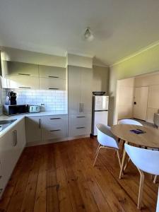 a kitchen with white cabinets and a table and chairs at Shepparton House in Shepparton