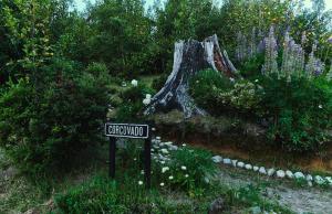 a sign in front of a garden with a tree at MA PU LODGE Futaleufu in Futaleufú