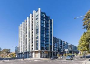 a tall white building with cars parked in a parking lot at Metropol - CBD pool Sleeps 7 in Canberra