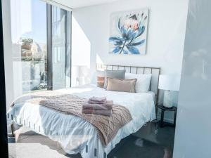 een witte slaapkamer met een bed met een handdoek erop bij Metropol - CBD pool Sleeps 7 in Canberra