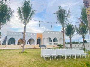 une réception de mariage devant un bâtiment blanc avec des palmiers dans l'établissement Morocco Villa Mui Ne, à Phan Thiết