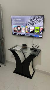 Una mesa de cristal delante de un televisor en una pared. en Cantinho do Aconchego, en Vila Velha