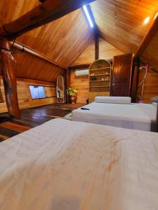 a bedroom with two beds in a room with wooden walls at Nhà Sàn Bên Suối in Buôn Ðũng