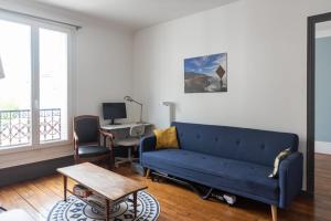 uma sala de estar com um sofá azul e uma mesa em Comfortable F4 near Petit-Montrouge em Paris
