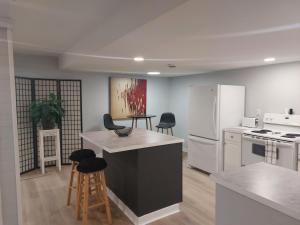 a kitchen with a white refrigerator and some chairs at Newly Renovated Suite in Regina