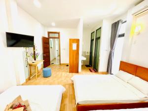 a hotel room with two beds and a television at Moon's House Homestay Quy Nhơn in Quy Nhon