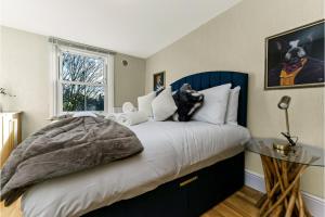 una camera da letto con un letto e un cane seduto sopra di Peaceful and Radiant 3BR Flat a Londra