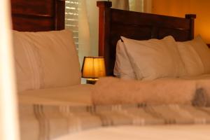 a bedroom with a bed with white pillows and a lamp at Room in Villa - Zambezi Family Lodge - Leopard Room in Victoria Falls
