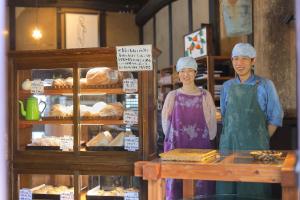 a man and a woman standing in front of a bakery at NIPPONIA 福住 宿場町 in Fukuzumi