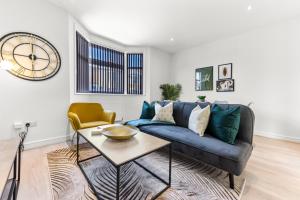 a living room with a blue couch and a clock at Modern and Hearty House in Enfield