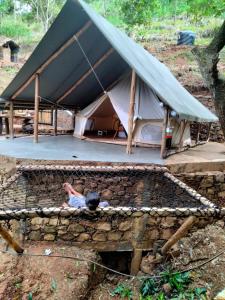 eine Person, die vor einem Zelt auf einer Wand liegt in der Unterkunft Ella Retreat Glamping Tent on Hill for Nature Lovers in Ella