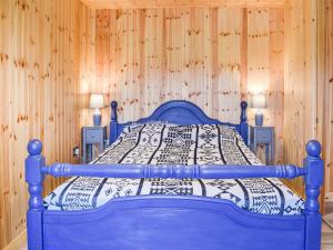 a blue bed in a room with wooden walls at Langston Farm Chalet in Shillingstone