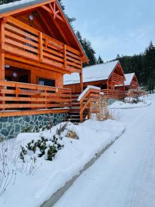 una cabaña de madera con nieve delante en Lopušná dolina Resort, en Vysoké Tatry