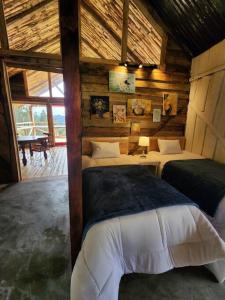 a bedroom with two beds in a wooden cabin at Hermosa y Nueva Cabaña de campo - La Candelaria Farm House in Cuenca