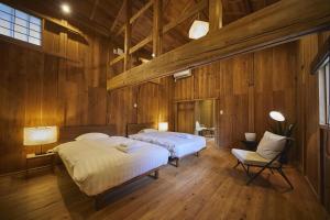 two beds in a room with wooden walls at NIPPONIA 福住 宿場町 in Fukuzumi