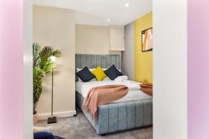a bedroom with a bed with yellow and blue pillows at Stylish and Snug Studio in Enfield