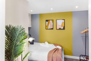 a bedroom with a yellow wall and a bed at Stylish and Snug Studio in Enfield