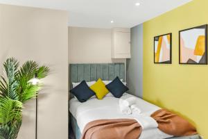 een slaapkamer met een bed met gele en blauwe kussens bij Stylish and Snug Studio in Enfield