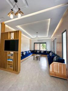 Il comprend un salon doté d'un canapé bleu et d'une télévision à écran plat. dans l'établissement Villa Marrakesh White Dreams, à Marrakech