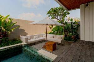 un patio con sofá y sombrilla junto a la piscina en Villa Sagrada in Canggu Bali, en Dalung