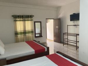a hotel room with two beds and a mirror at Nugasewana Guest in Anuradhapura