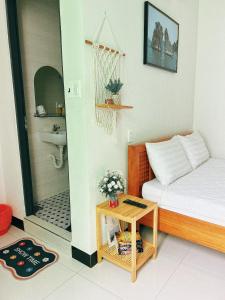 a small room with a bed and a table and a bathroom at NẮNG HOMESTAY in Tuy Hoa