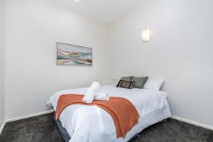 a white bedroom with a bed with a towel on it at Serpentine Park on View in Bendigo